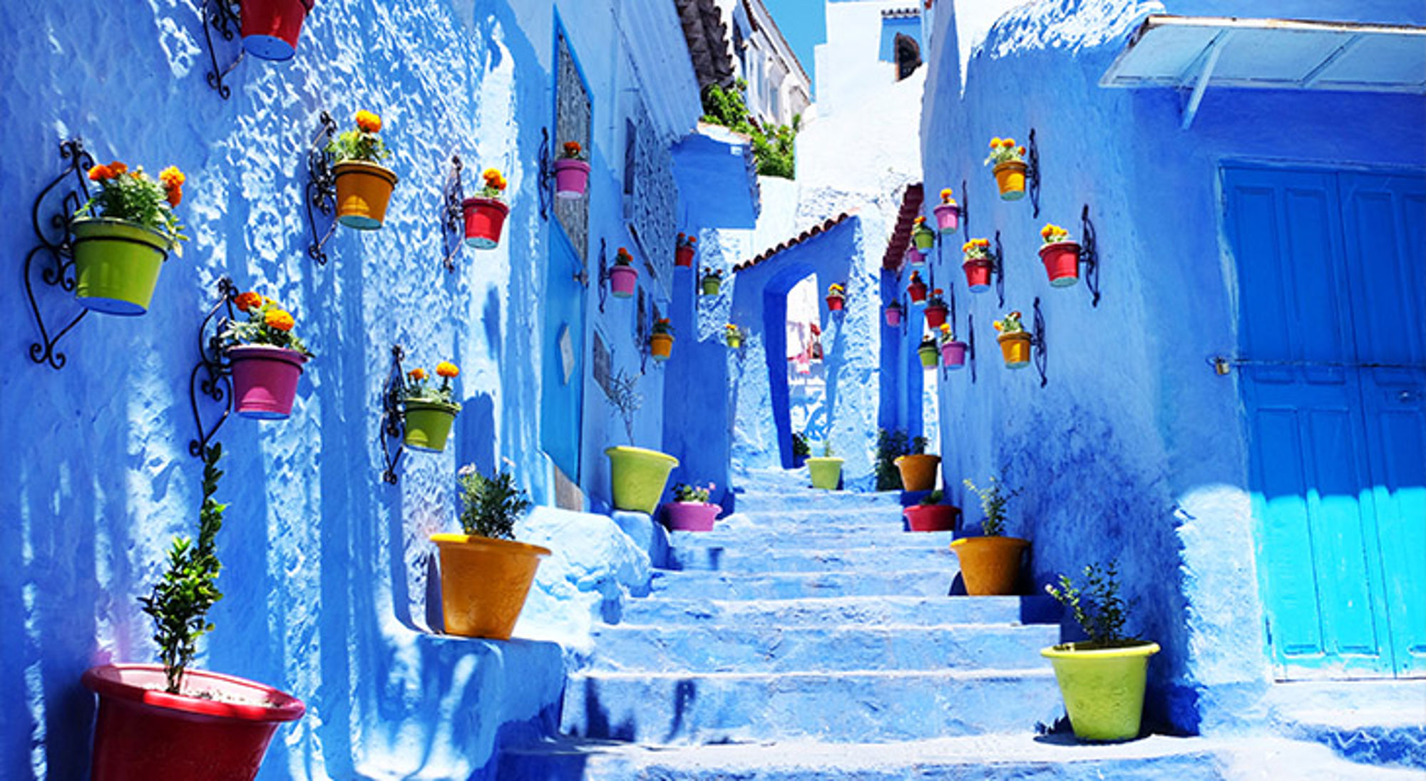 Chefchaouen Marokko Blauwe straat met trappen en kleurrijke bloempotten aan de muren in Chefchaouen, Marokko.