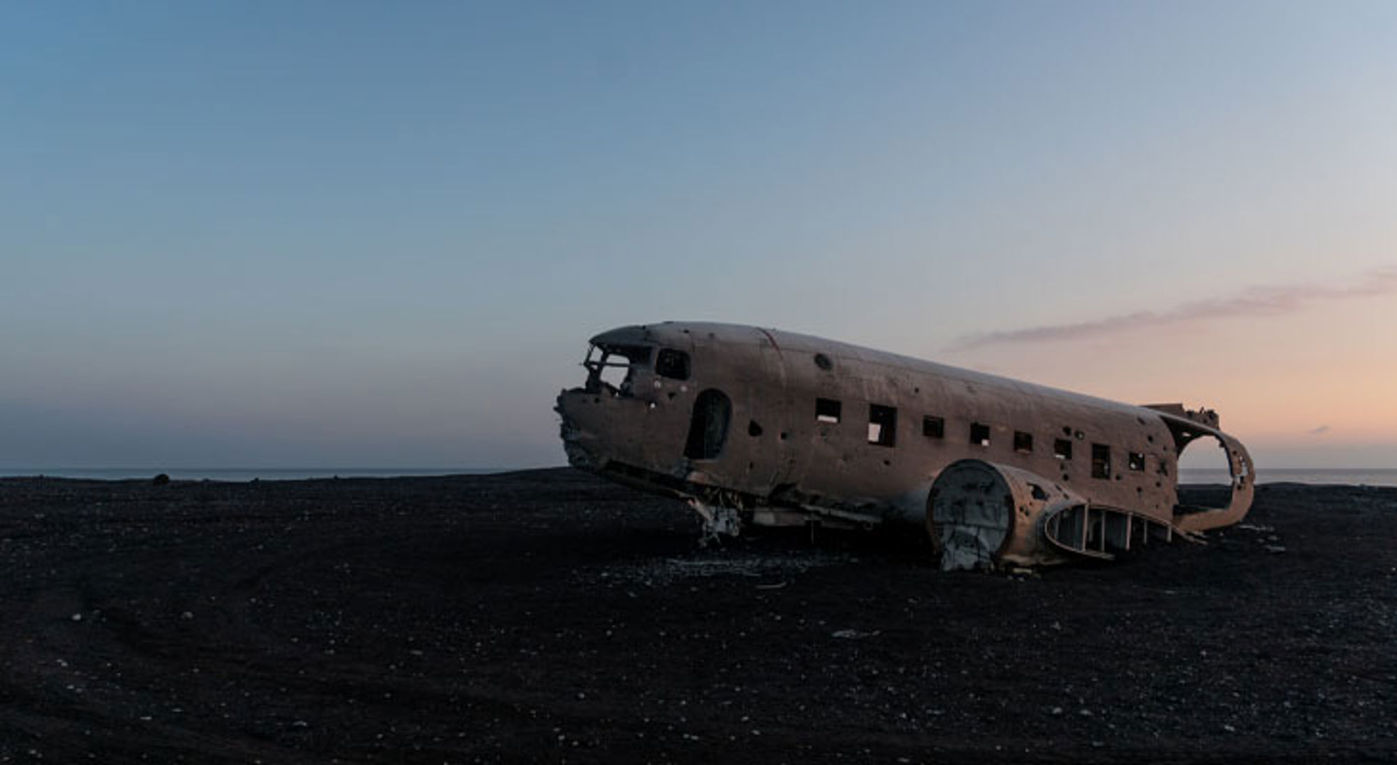 Vliegtuigwrak IJsland Vliegtuigwrak op het zwarte zandstrand Sólheimasandur in IJsland bij zonsondergang.