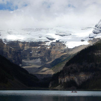 Kano op bergmeer met gletsjers en besneeuwde toppen in de Canadese Rocky Mountains.