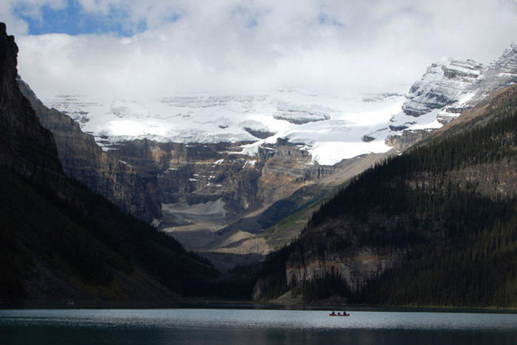 Kano op bergmeer met gletsjers en besneeuwde toppen in de Canadese Rocky Mountains.