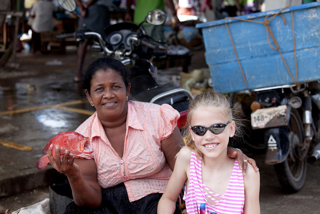Vrouw en meisje op een markt in Sri Lanka, met een rode vis in de hand.