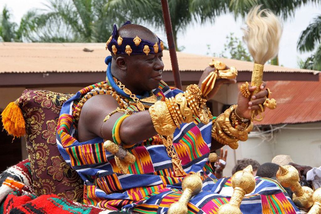 Traditionele ceremonie in Ghana met man in kleurrijke kente en gouden sieraden tijdens groepsrondreis Ghana, Togo en Benin.