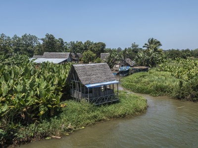 Rivierdorp met rieten huisjes en boten tussen weelderig groen langs de route Madagascar, 19 dagen.