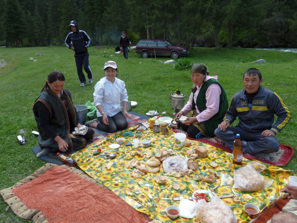 Picknick met lokale familie op een kleed in de natuur tijdens een groepsrondreis Kirgistan (Kirgizië).