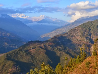 Uitzicht over groene heuvels en besneeuwde Himalaya-toppen tijdens de Nepal familiereisroute.