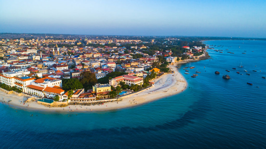 Stone Town op Zanzibar met wit zandstrand, kleurrijke daken en dhowboten in de Indische Oceaan.
