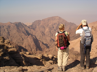 Wandelaars met rugzakken kijken uit over de bergen bij Wadi Rum tijdens de route Jordanië en Israël, 15 dagen.