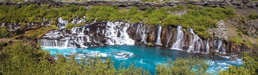 Waterval met helderblauw water in groen landschap in IJsland tijdens een groepsrondreis.