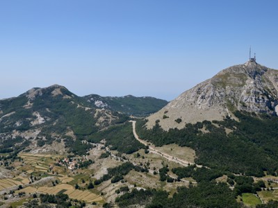 Uitzicht op de berg Lovćen met zendmast en dal met akkers in Montenegro.