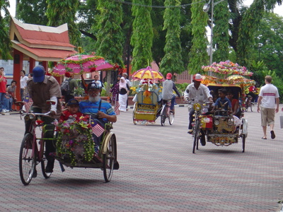 Versierde fietstaxi’s (trishaws) met parasols op straat in Melaka, Maleisië.