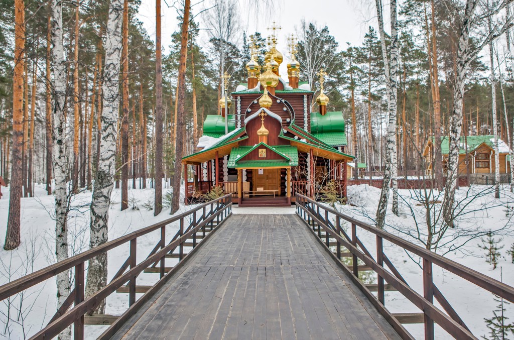 Houten orthodoxe kerk met gouden koepels in een besneeuwd bos langs de Trans-Siberië Expres-route.