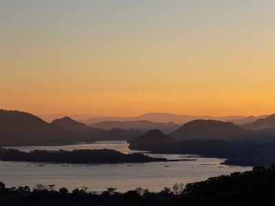 Zonsondergang boven het Meer van Yojoa met silhouetten van heuvels, Honduras.
