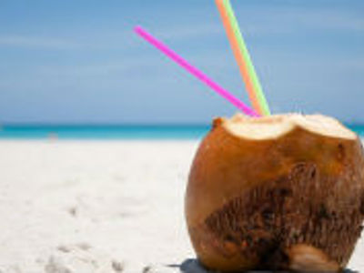 Kokosnoot met rietjes op wit zandstrand aan zee in Cuba.