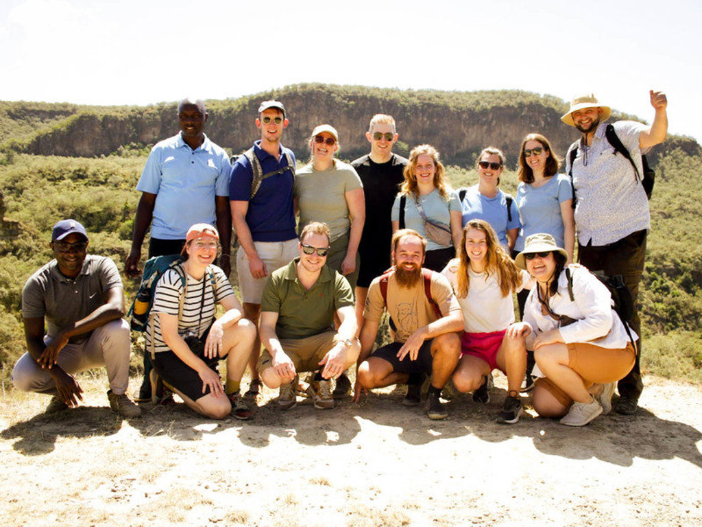 Groepsfoto van 22-35ers tijdens rondreis Kenia & Tanzania met uitzicht op een groene vallei en kliffen.
