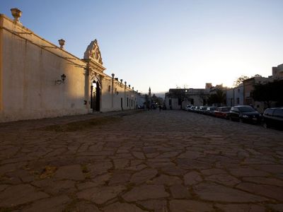 Zonsondergang bij een historisch gebouw aan een geplaveide straat in Salta tijdens de route Argentinië, Bolivia en Peru.