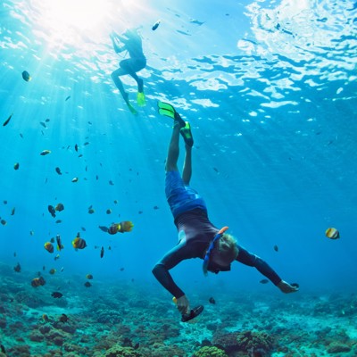 Snorkelaars bij Tabuhan eiland boven het koraalrif, omringd door tropische vissen.