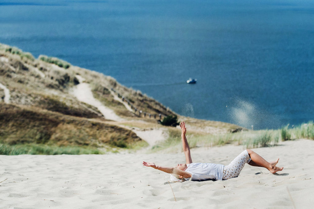 Kind geniet van zandduinen aan de kust tijdens familiereis Polen en Baltische Staten.