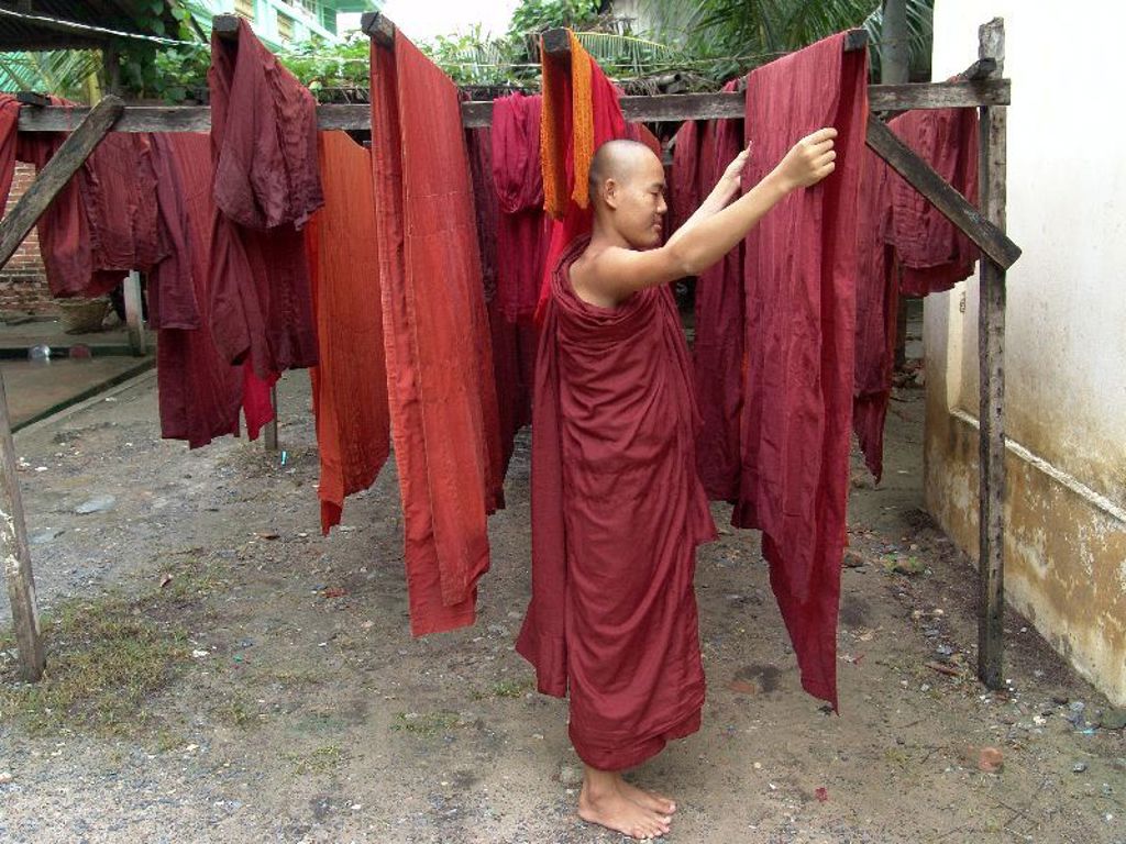 Boeddhistische monnik hangt rode gewaden te drogen in Myanmar.