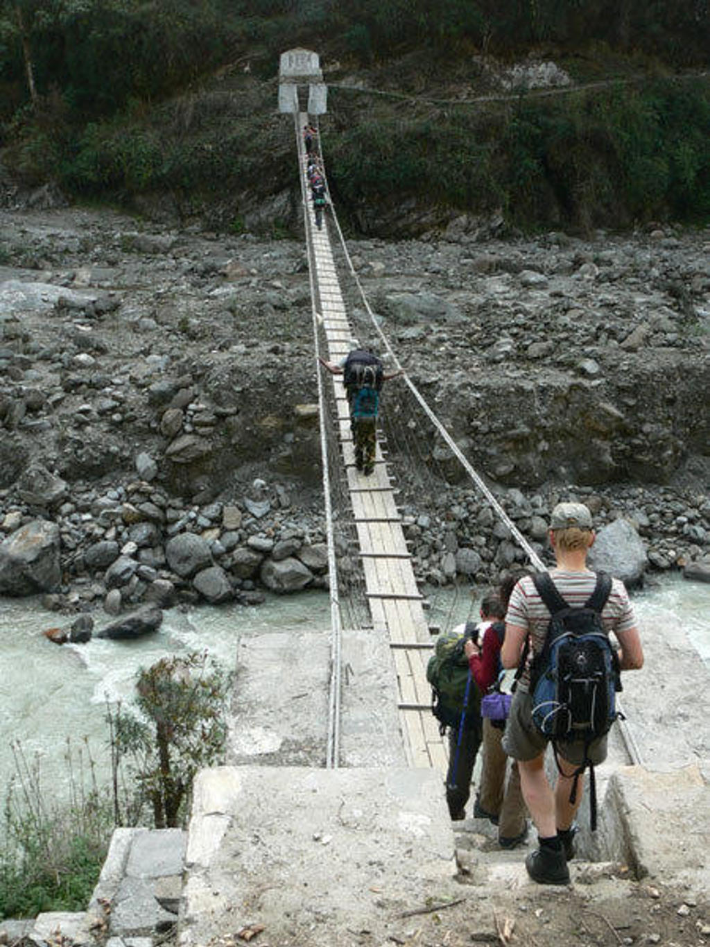 Trekkers steken een hangbrug over een rivier over tijdens de Everest-trektocht in Nepal.