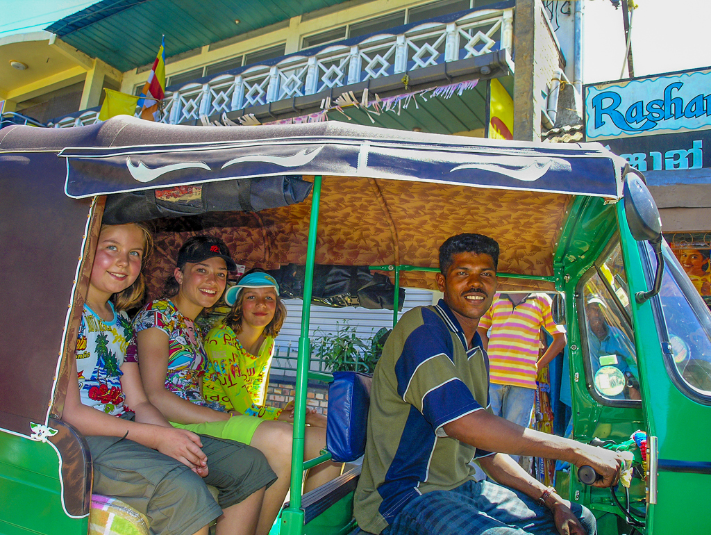 Gezin in een kleurrijke tuktuk tijdens een familiereis langs de hoogtepunten van Sri Lanka.