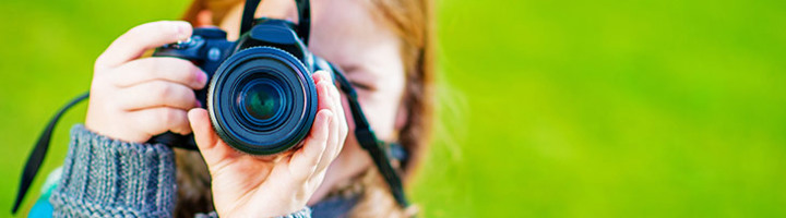Kind maakt een foto met een spiegelreflexcamera, passend bij fotografietips voor kinderen.