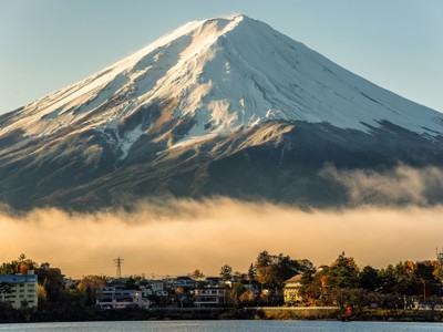 Uitzicht op de besneeuwde Mount Fuji boven een mistige laag en dorpjes aan de voet, Japan.