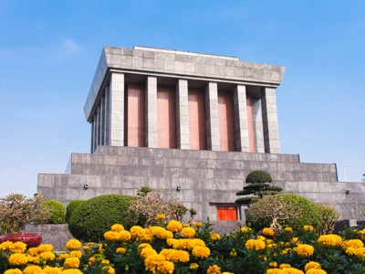 Ho Chi Minh Mausoleum in Hanoi met bloeiende gele bloemen, onderdeel van de Route Vietnam.