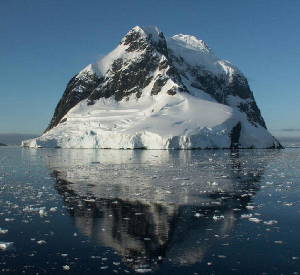 Sneeuwbedekte ijsberg in Antarctica weerspiegeld in kalm zeewater tijdens groepsrondreis Antarctica, Falklands en South Georgia.