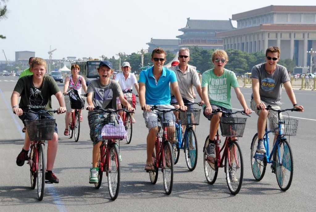 Gezin fietst door Beijing tijdens familiereis China, met Tiananmenplein op de achtergrond.