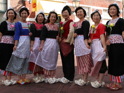 Vrouwen in traditionele Nederlandse klederdracht met tulpen, tijdens een straatfestival in Volendam.