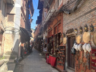 Smalle straat in Kathmandu met souvenirwinkels, maskers en hangende kabels op de Route Nepal Everest Base Camp.