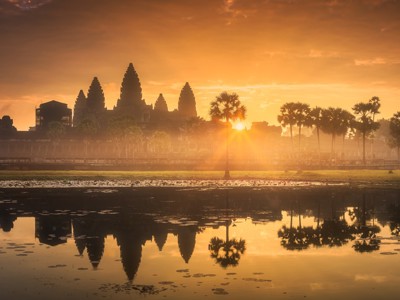 Zonsopkomst bij Angkor Wat met palmbomen en spiegeling in het water, Cambodja.