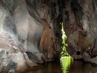 Rivier in een grot met hoge rotswanden en een smalle opening naar het groen in Cuba.