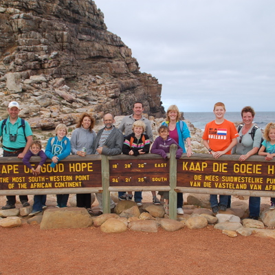 Gezin bij het bord van Kaap de Goede Hoop tijdens een familiereis door Zuid-Afrika en eSwatini.