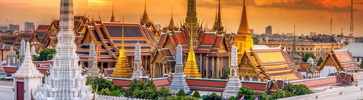 The Grand Palace in Bangkok bij zonsondergang, met kleurrijke tempeldaken en gouden pagodes.