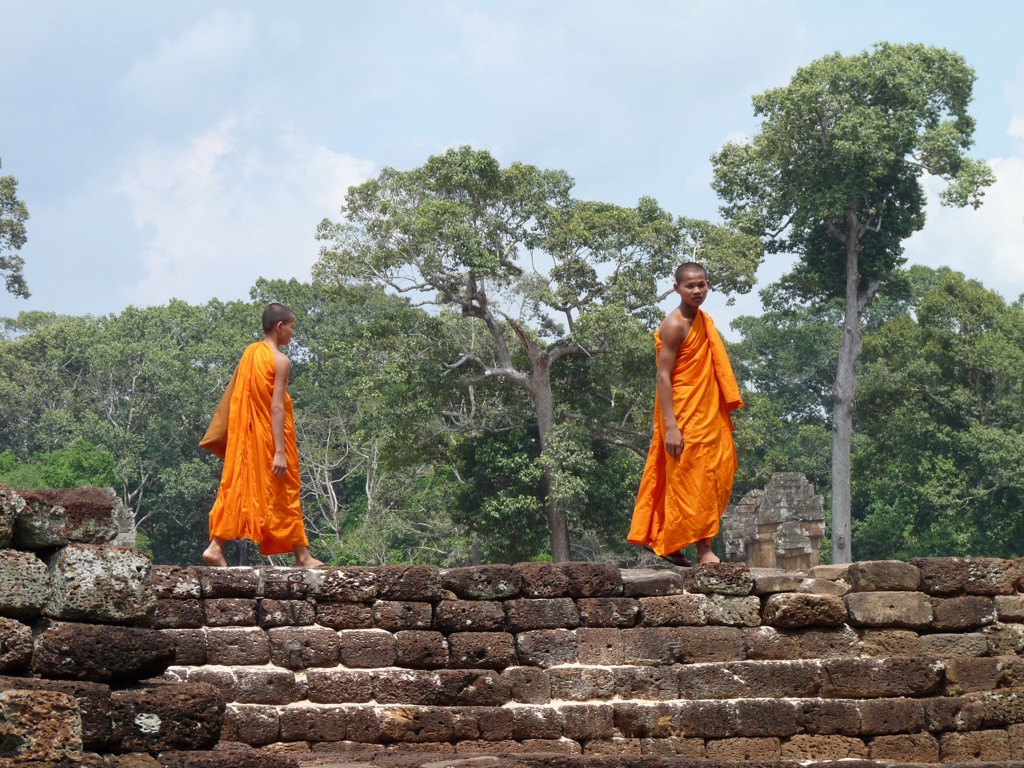 Boeddhistische monniken lopen over eeuwenoude tempelruïnes op de Route Indochina in Cambodja.