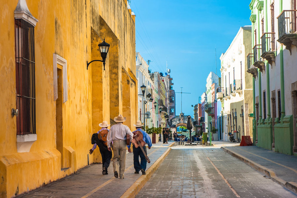 Mannen met sombrero’s lopen door een kleurrijke straat in een historische stad in Mexico.