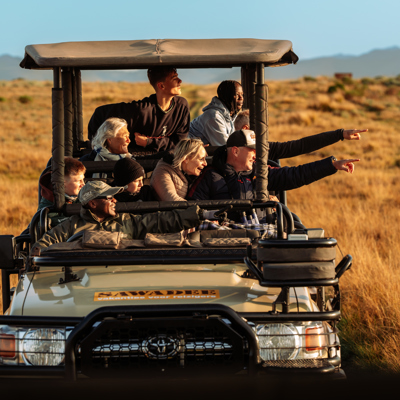 Gezin op safari in open jeep in Zuid-Afrika, wijzend naar wild op de savanne.