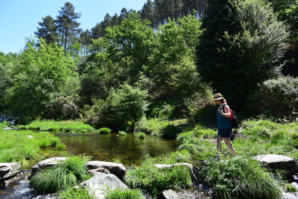 Wandelaar steekt een beek over in het groene landschap van de Dourovallei in Portugal.