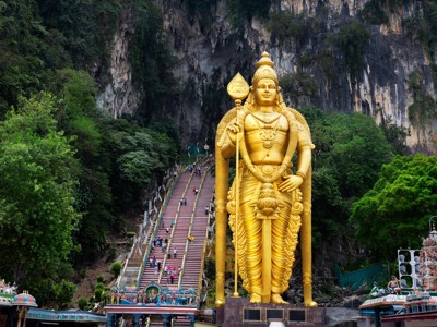 Gouden Murugan-beeld bij de Batu Caves met kleurrijke trap naar de grotten, Kuala Lumpur, Maleisië.