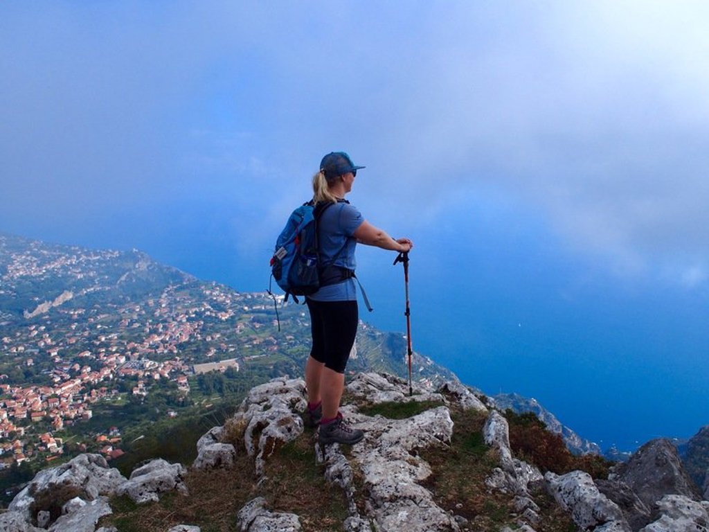 Wandelaar met rugzak en wandelstokken op een pad aan de Amalfikust, Italië.