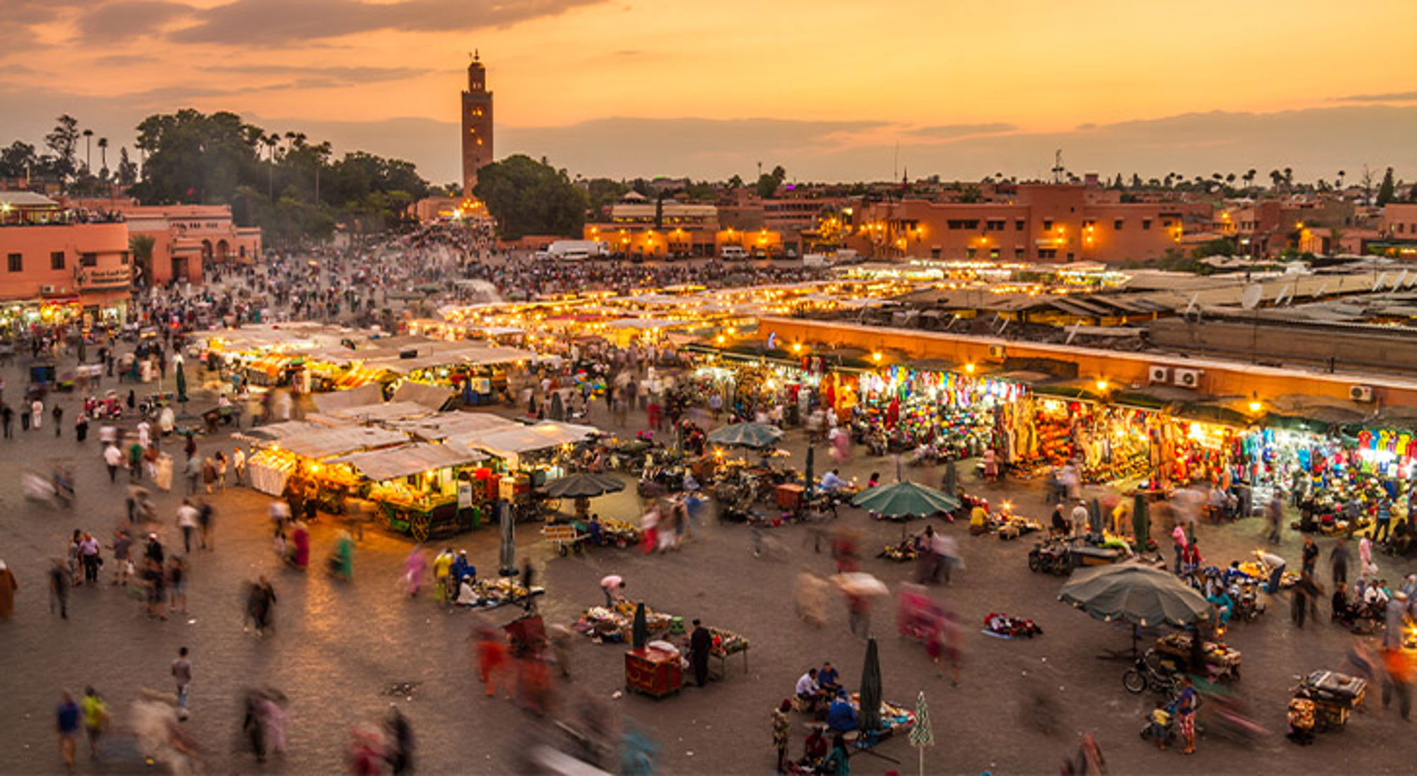 Marrakech Marokko Avondbeeld van de Jemaa el-Fna markt in Marrakech met verlichte kraampjes en de Koutoubia-minaret op de achtergrond.