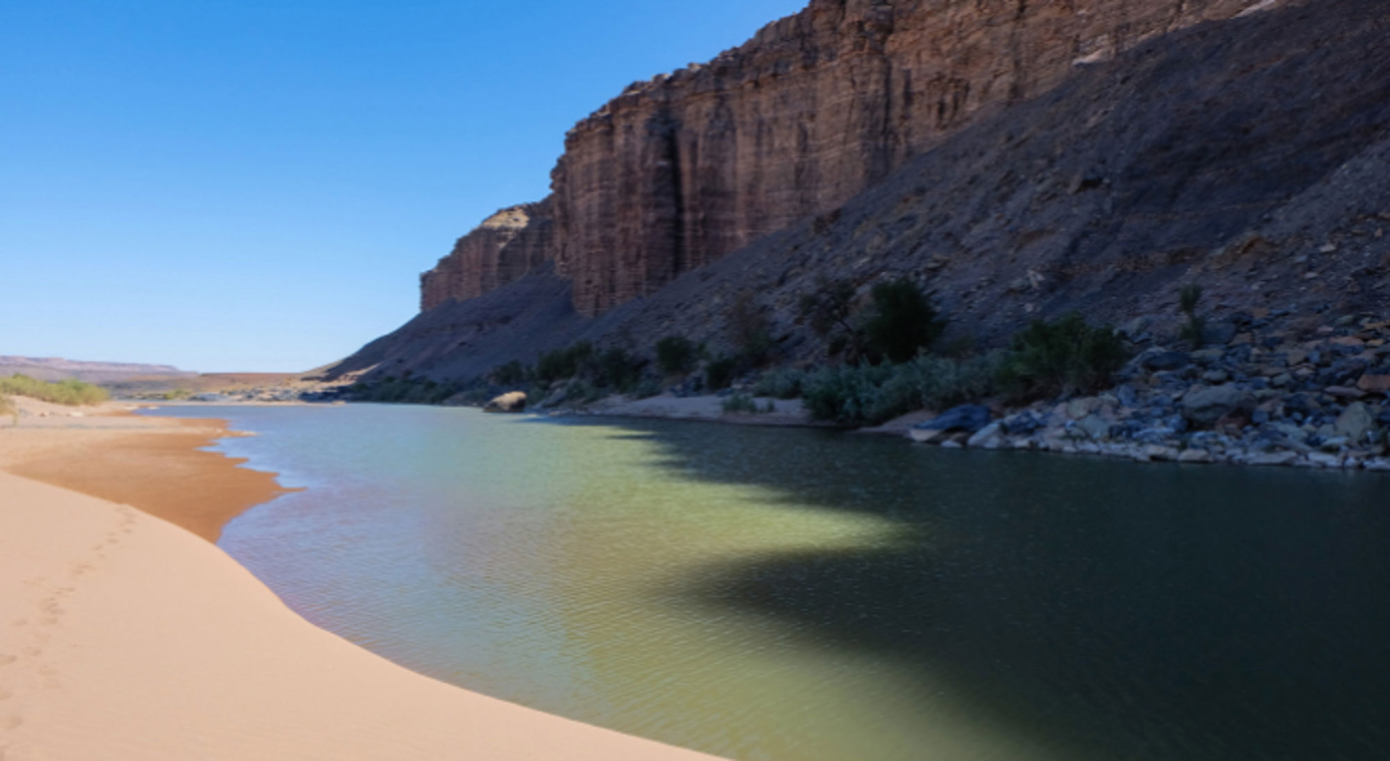 Rivier met zandbank langs hoge rotswanden in Namibië.