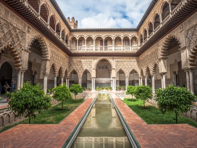 Binnenhof van het Alcázar in Sevilla met Moorse bogen, sierstucwerk, sinaasappelbomen en waterbassin.