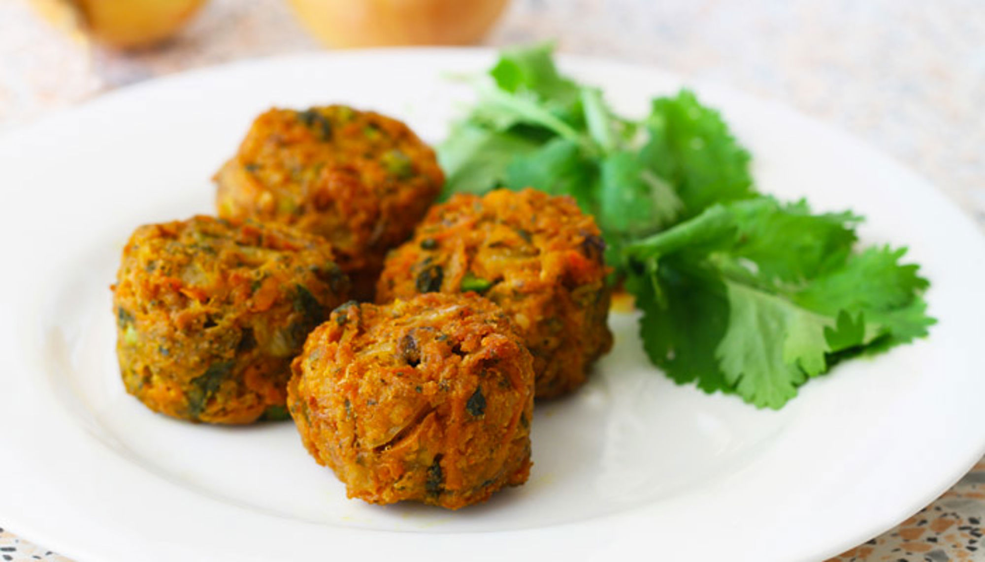 groente pakora gerecht uit india Vier falafelballetjes op een wit bord met verse koriander.