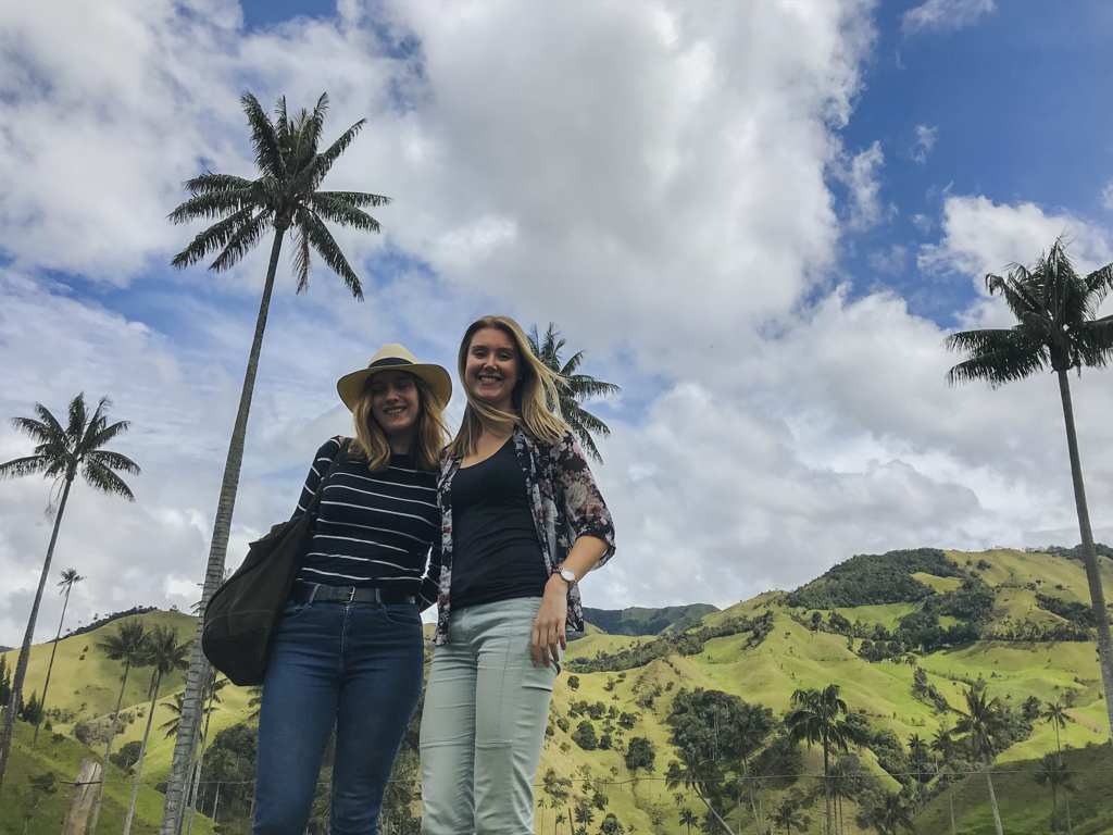Twee reizigers poseren tussen hoge palmen en groene heuvels tijdens een 22-35ers reis door Colombia.