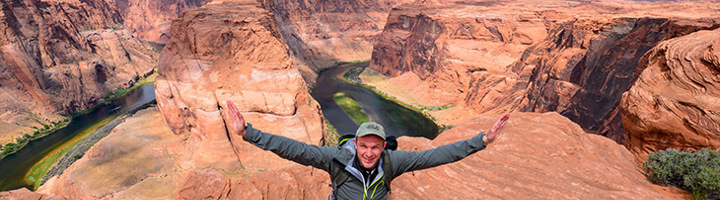 Reiziger met gespreide armen bij Horseshoe Bend in Arizona, Verenigde Staten.