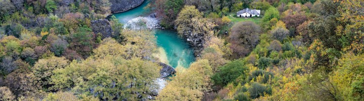 Turquoise rivier in de Vikos Kloof, omringd door herfstbossen en rotswanden in Griekenland.