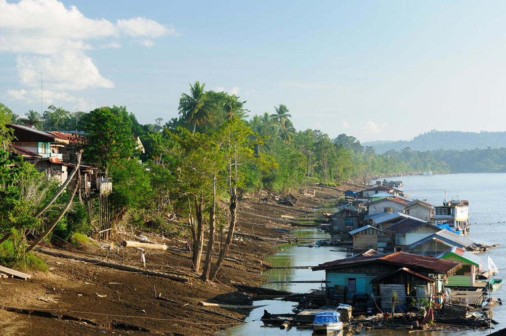 Rivierdorp met houten huizen langs de oever in Kalimantan, Indonesië.