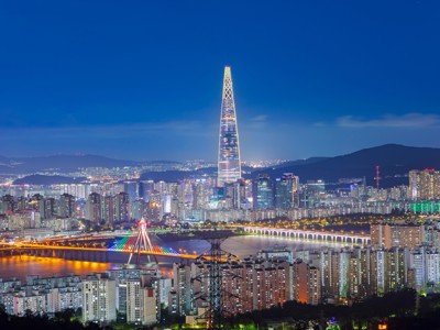 Nachtelijk uitzicht op de skyline van Seoul met de verlichte Lotte World Tower en brug over de Han-rivier.